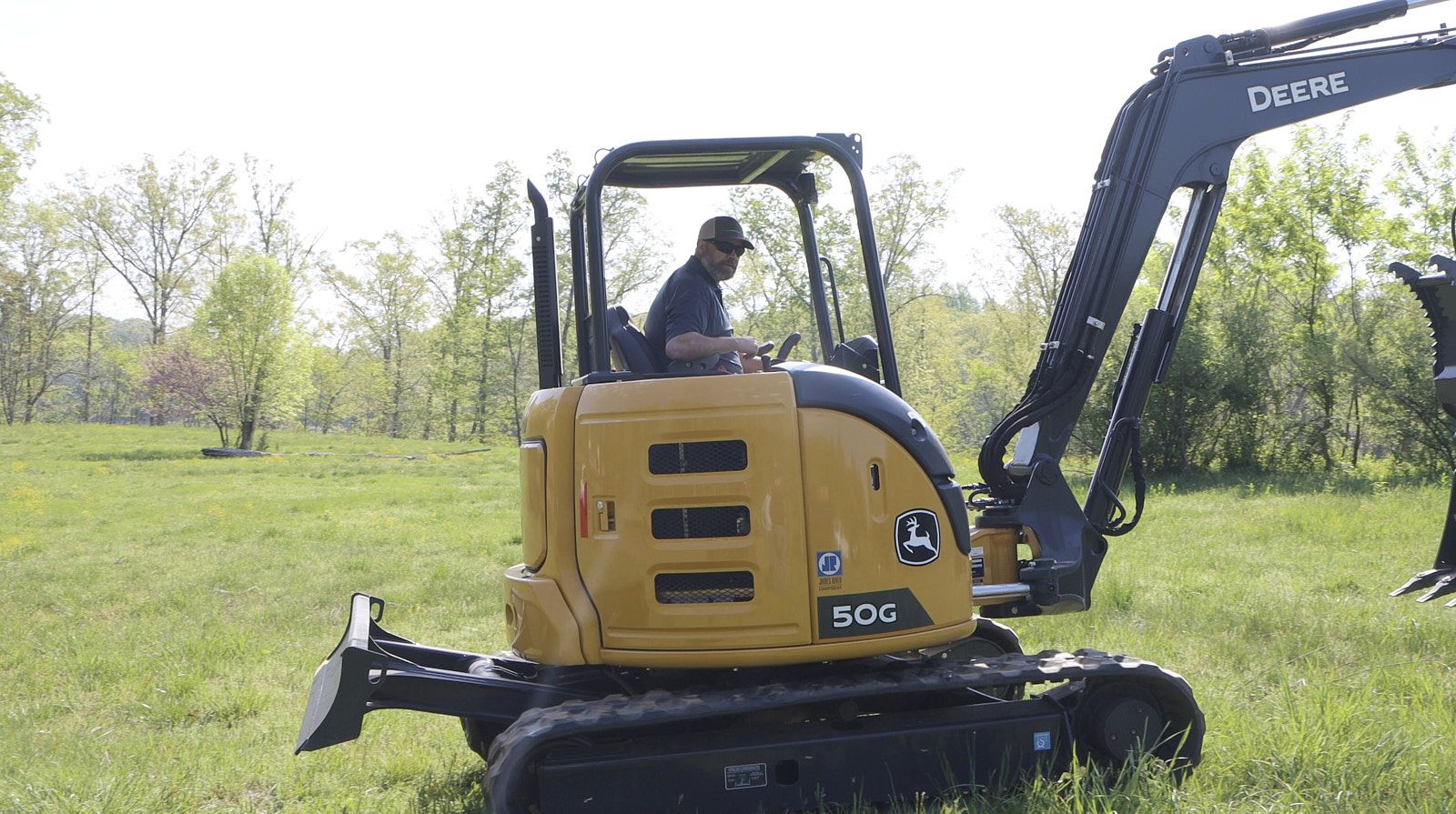 Professional Tractor Driver From Soils Inc With A Hat In A Yellow Tractor Resting In A Grassy Green Site