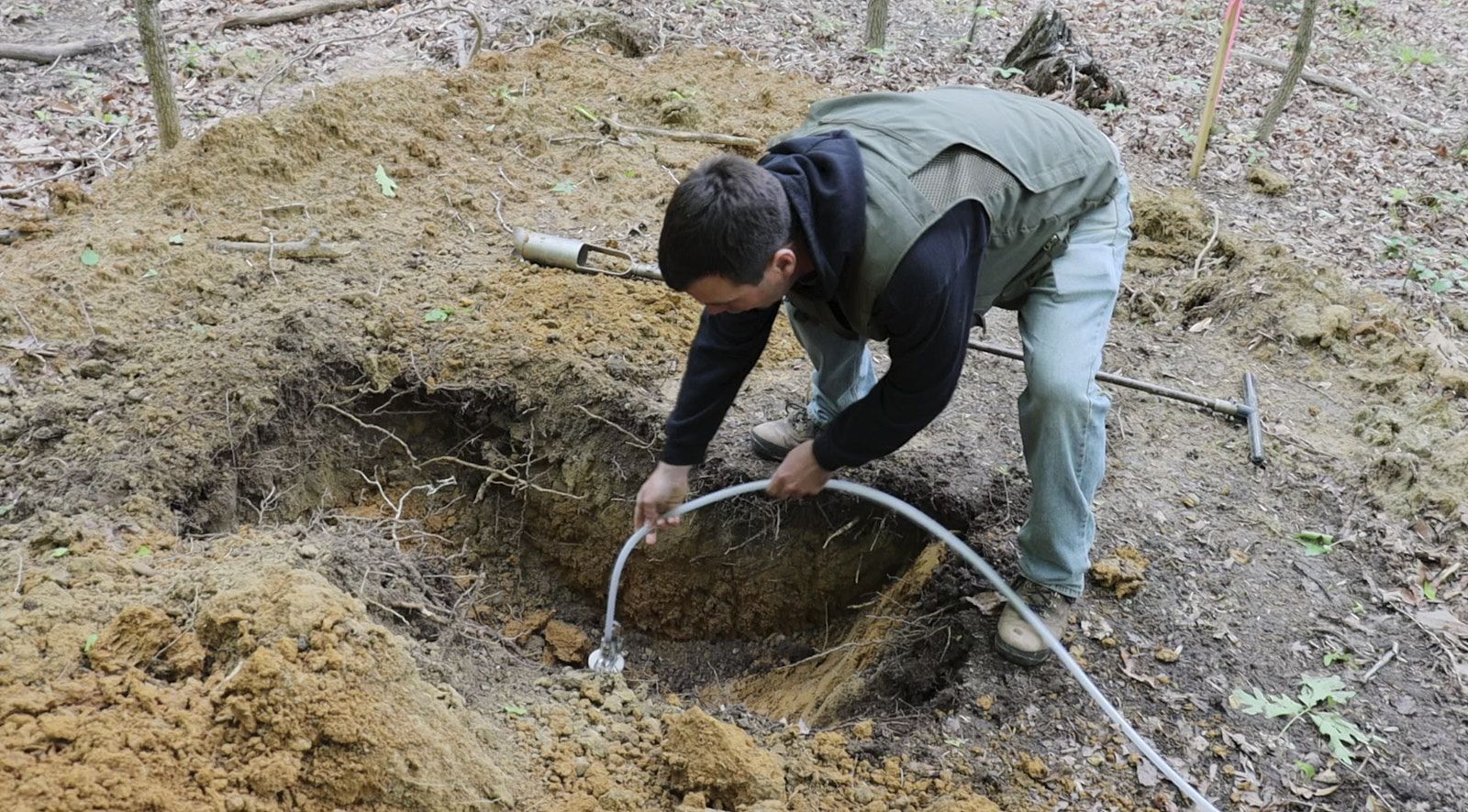 A Professional Worker From Soils Inc Mounted A Small Pipe Inside A Dug Hole As Part Of The Soil Testing Process