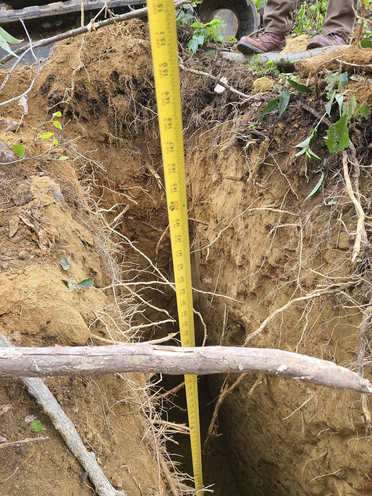 A Measurement Tape Aligned Vertically Inside A Narrow Dug Hole To Measure Its Depth By The Experts Of Soils Inc