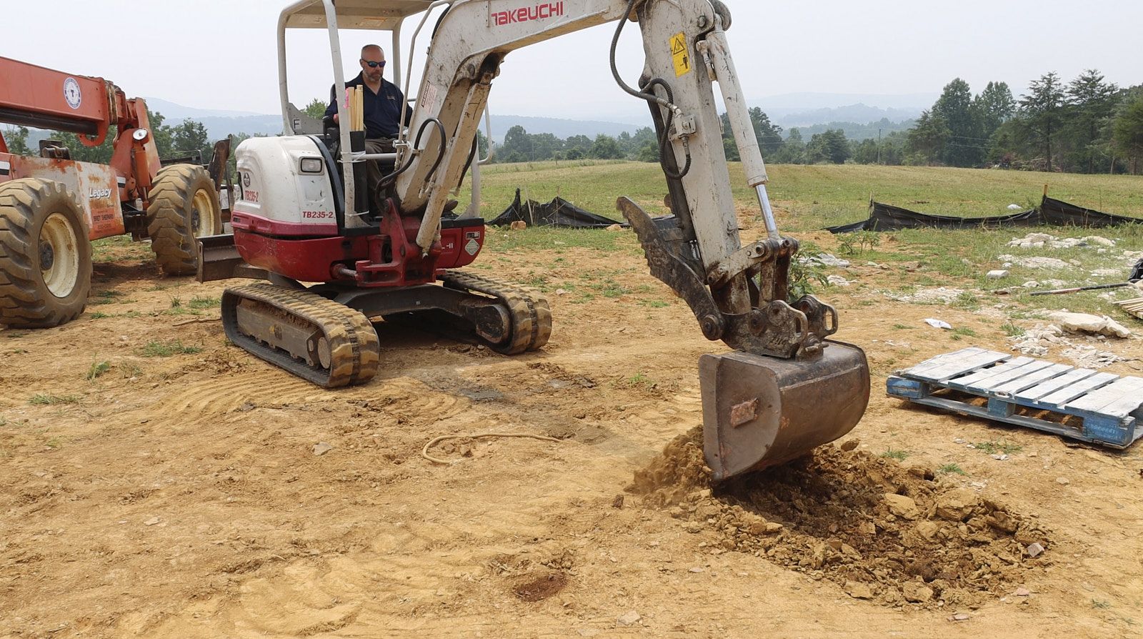 A Driver From Soils Inc Operating A Tractor Digging And Collecting Soil In The Backhoe At A House Construction Site