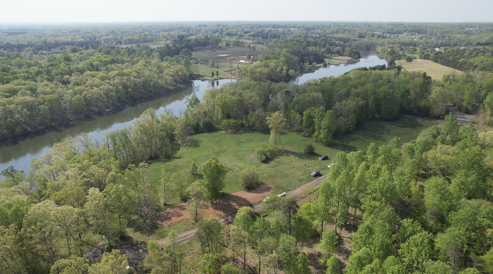 A Drone Shot Of A Beautiful Green Area With Numerous Trees Plants Grass And Some Vehicles On The Road In The Middle