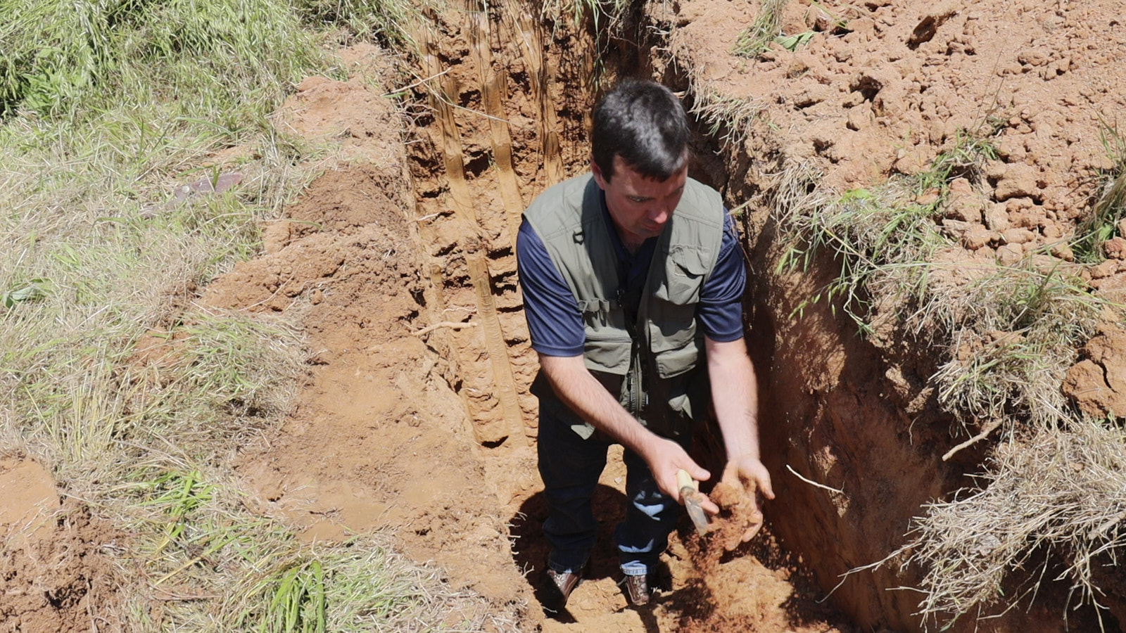 A Man From Soils Inc Inside A Dug Hole In The Soil Examining Soil Samples Under The Trench