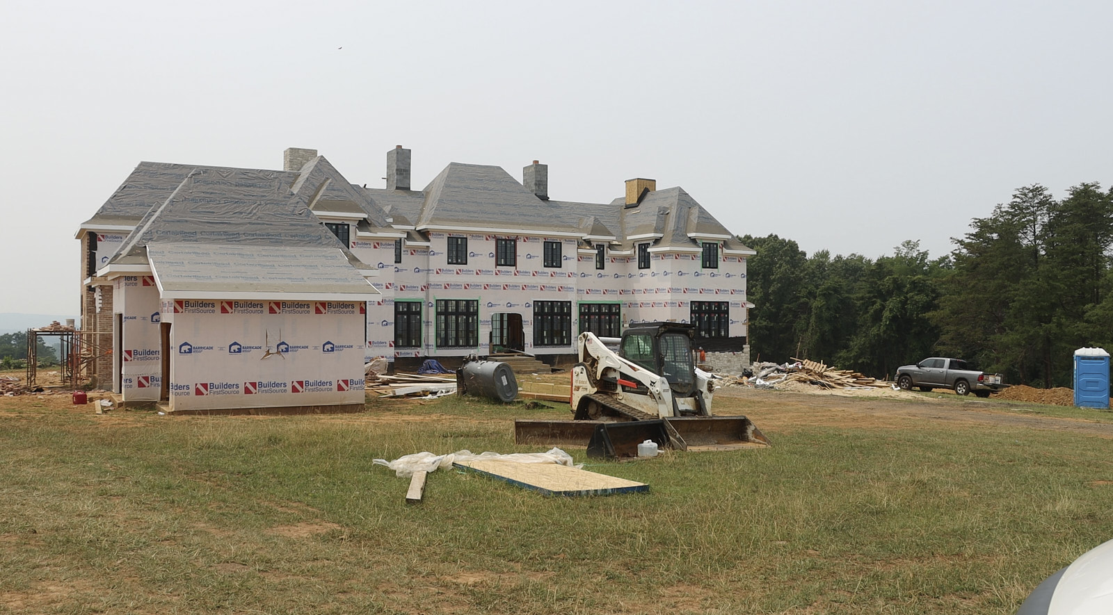 Wide Angle Shot Of A Newly Constructed House By Soils Inc Building Material And A Tractor Parked Outside
